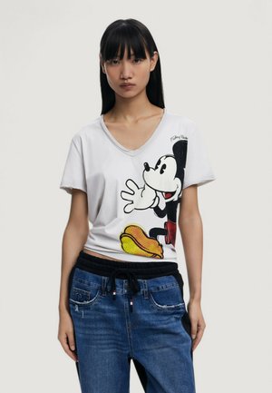 T-shirt blanc à col en V avec un graphique noir et rouge de Mickey Mouse et un design de hot-dog. Associé à un jean en denim bleu avec cordon de serrage.