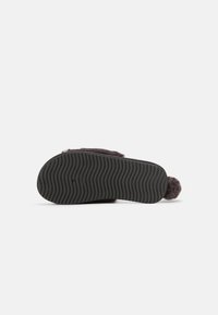 Dark gray slipper featuring a textured black rubber sole, with a soft upper material and a small pom-pom detail at the back.