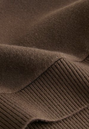 Ruda medžiaga su minkšta tekstūra ir suribotu raštu palei kraštą, turinti lygius, šiek tiek pūkuotus skyrius.