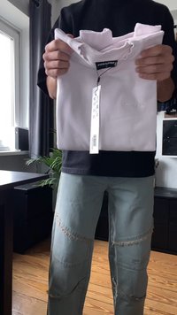 Λευκό κοντομάνικο μπλουζάκι κρατημένο από ένα άτομο, με στρογγυλή εκτύπωση στον λαιμό και ετικέτα "PEGADOR". Ελαφρύ ύφασμα, ομαλή υφή, ξεχωριστή ετικέτα.