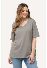 Camiseta gris de manga corta con escote en V, con motas multicolores. Tela suave con un corte relajado, combinada con jeans de color azul claro.