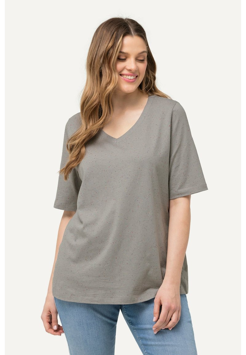 Camiseta gris de manga corta con escote en V, con motas multicolores. Tela suave con un corte relajado, combinada con jeans de color azul claro.