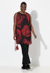 Top senza maniche con grande stampa di rosa rossa su sfondo nero, con dettagli in perline nere, abbinato a pantaloni neri svasati e tacchi con bordo in pelliccia.