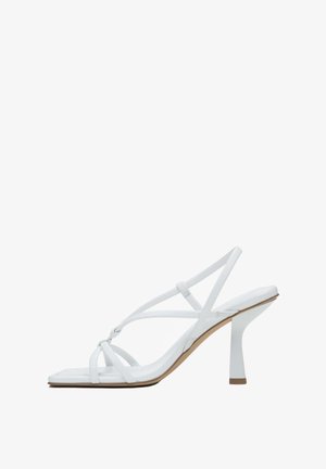 White high-heeled sandal with thin straps, square toe, and a block heel. Smooth texture with a minimalist design and neutral color.