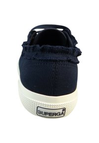 Granatowe sneakersy z płótna o fakturowanej górze, z falbaną przy kołnierzu i białą gumową podeszwą z wzorem w diamenty. Logo umieszczone po bokach.