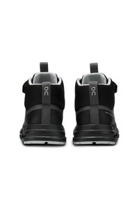 Chaussures de randonnée noires avec une conception montante, dessus en textile lisse, accents gris contrastants et semelle en caoutchouc durable avec motifs de traction.