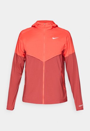 Tofarget rød Nike zip-up hettejakke med lange ermer, frontglidelås, sidelommer, og en liten hvit logo på brystet og mansjetten.