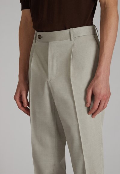 Jasnoszare, dopasowane spodnie o gładkiej strukturze, z zapięciem na guzik i plisami z przodu, prezentowane razem z brązową koszulą.
