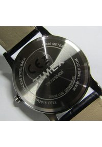 Timexi kell, millel on roostevabast terasest puus ja beež nahkrihm, koos hõbedaste aktsentidega. Omab veekindlust kuni 30 meetri sügavusele.