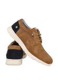 Zapatos de ante marrón con un acento en el tacón de color azul marino, suela blanca estriada y cordones marrones. El interior presenta un patrón a rayas.