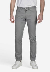 Lichtgrijze chino's van katoen, met een slim fit ontwerp, voorzakken en een knoopsluiting met een ritssluiting. Draagt met witte sneakers.
