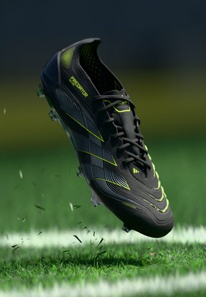 Black soccer shoe with neon green accents, featuring a textured upper, sleek design, and cleats for traction on grass surfaces.