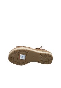 Brown suede sandal with a textured rubber sole, featuring a wide strap and adjustable buckle. Logo visible on the sole.