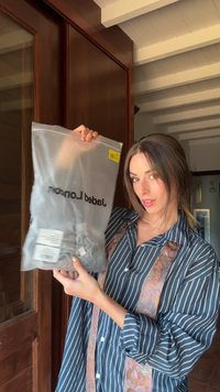 Prozoren plastičen vrečka s sivo obleko, označena z "Jaded Ldn," z rumeno cenovno oznako in belimi podrobnostmi o izdelku na hrbtu.