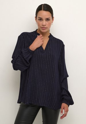 Marineblouse met ruches kraag, lange mouwen en verticale zilveren strepen. Ontspannen pasvorm met zijslitsen en zachte textuur.