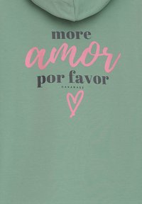 Grüne Kapuzenjacke mit dem Text "more amor por favor" in Pink und Dunkelgrau, versehen mit einem Herz-Graphic. Weiches Material, lässiges Design.