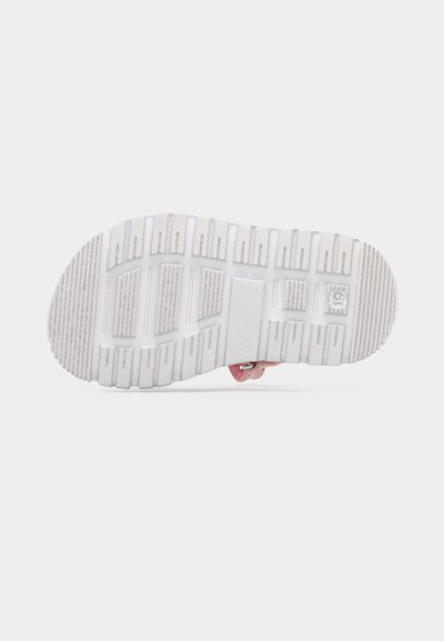 Λευκή λαστιχένια σόλα παιδικού σανδαλιού με ροζ λουράκι και μεταλλική αγκράφα, εμφανίζεται από κάτω σε απλό λευκό φόντο.