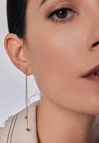 Złote kolczyki na wisiorkach posiadają dwa okrągłe akcenty oraz delikatny łańcuszek, prezentując minimalistyczny design o wypolerowanym wykończeniu.