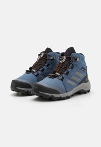 Bottes de randonnée bleues avec des accents noirs et gris, tige en mesh et synthétique, caractéristiques imperméables, bandes réfléchissantes et semelles à traction.