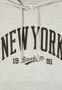 Jasnoszara bluza z kapturem i regulowanym sznurkiem. Czarny nadruk z napisem "NOWY JORK" oraz "Brooklyn 1991" w wyraźnej czcionce. Miękka w dotyku.