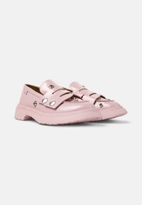 Rosa slip-on skor med flera remmar och silverdetaljer, placerade mot en enkel bakgrund som framhäver deras blanka finish och souldesign.