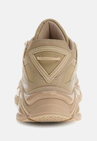 Beige sportcipők textúrázott bőr és hálós felsőrészével, hátuljára háromszög alakú részlettel, valamint párnázott, mintás talppal.
