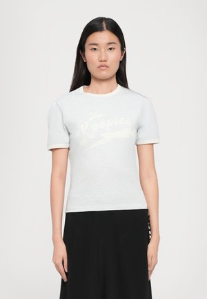 T-shirt à manches courtes en maille côtelée gris clair, avec un col rond et des accents blancs. Présente le graphique "The Kooples" dans un style usé sur le devant.