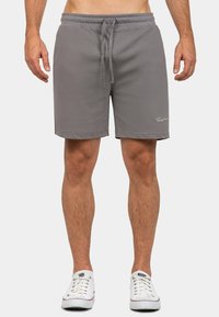 Pantaloni corti grigi in felpa con cintura elastica e cordino. Presentano tasche laterali e un piccolo dettaglio del logo nella parte anteriore in basso.