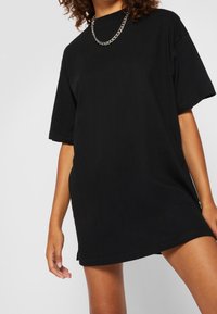 Zwarte oversized t-shirt van katoen, met een ronde halslijn, korte mouwen en een rechte zoom. Zichtbare kettinghalsketting accent.