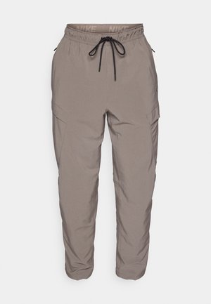 Pantalones cargo de Nike en gris claro, con una cintura elástica con cordón, bolsillos laterales y un ajuste tapered. Textura de tela suave.