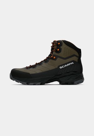 Oliven grønn og svart Scarpa turstøvel med oransje detaljerte lisser og robust såle, sidevisning på hvit bakgrunn.