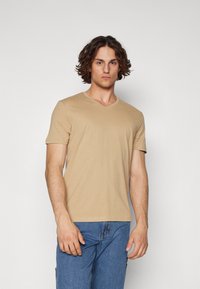 Short-sleeve, beige V-neck T-shirt made of soft material. Features a smooth texture with a regular fit and minimal detailing.