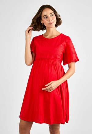 Rotes Schwangerschaftskleid mit kurzen Rüschensäumen, rundem Ausschnitt und gerafftem Taillenbereich. Der weiche, leichte Stoff hat ein strukturiertes Design.