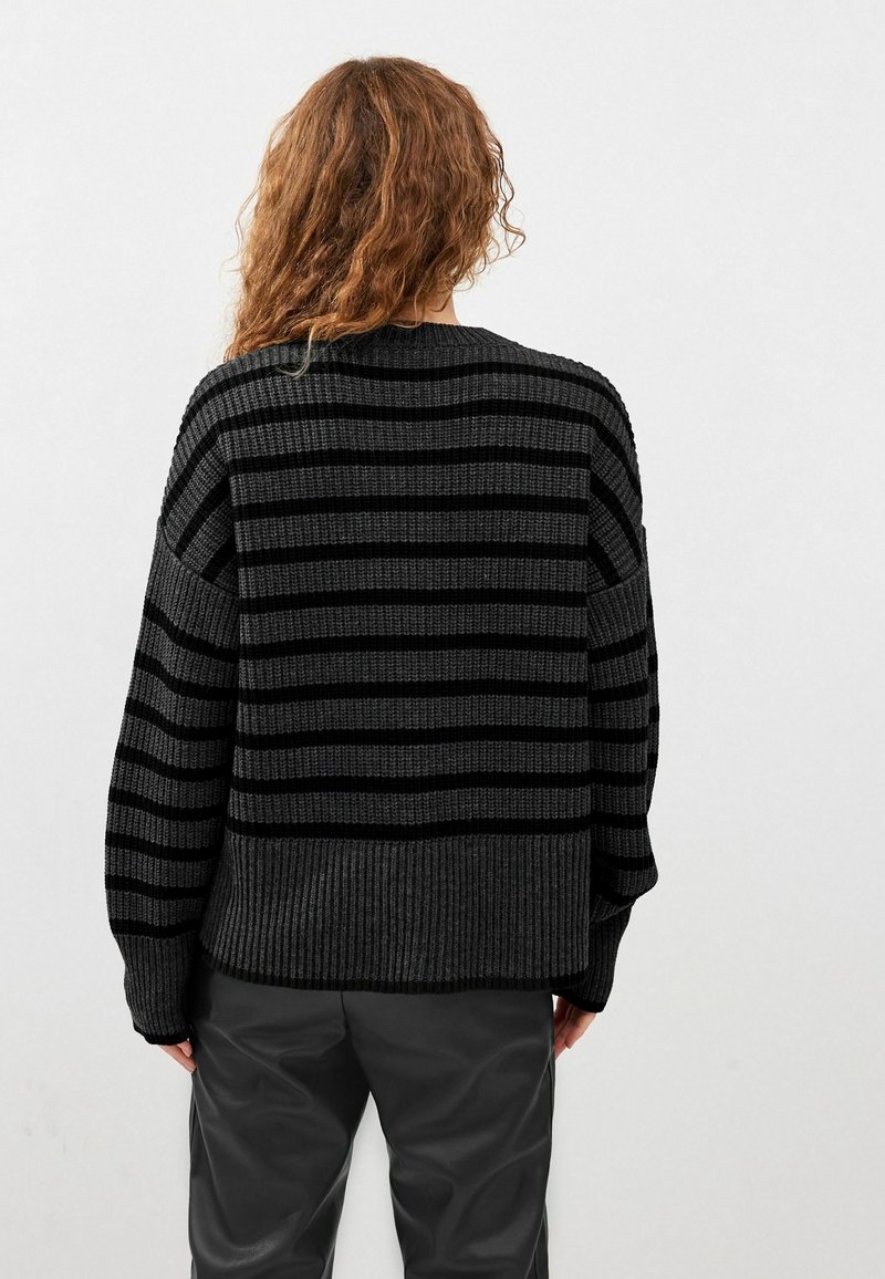Pull tricoté rayé noir et gris avec une texture côtelée, doté d'une coupe décontractée et d'épaules tombantes, visible de dos.