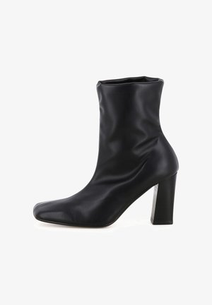 Bottine noire en cuir lisse, avec un design ajusté, un bout pointu et un talon carré haut. Hauteur approximative : 10 cm.