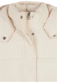 Beige dunjakke med høy krage, frontlukking med glidelås og metallsnapper. Glatt stoff med quiltet mønster.