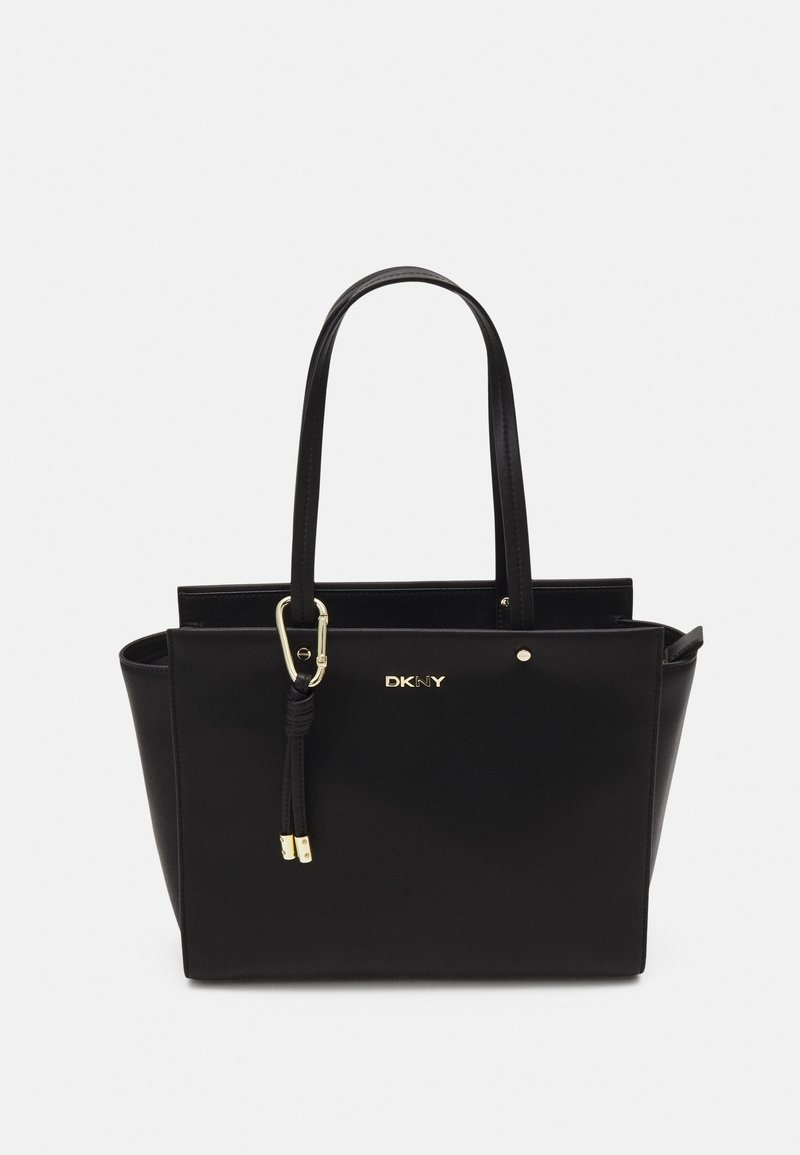 Sac cabas noir DKNY avec deux anses, logo doré et accents dorés sur fond blanc.