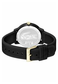 Bracelet de montre en silicone noir avec une finition texturée, boucle dorée, et fond de boîtier en acier inoxydable avec un logo de crocodile.
