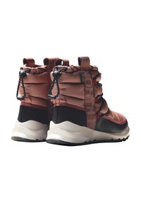 Botas en un color óxido con un upper de nailon acolchado, cordones elásticos y una suela de goma negra. Presenta un lazo en el talón y acentos texturizados.
