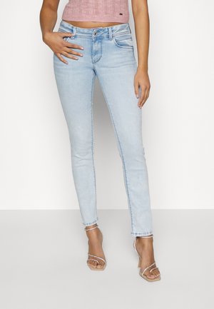Light blue skinny jeans with a medium rise, featuring a classic five-pocket design and slight fading. Paired with strappy clear heels.