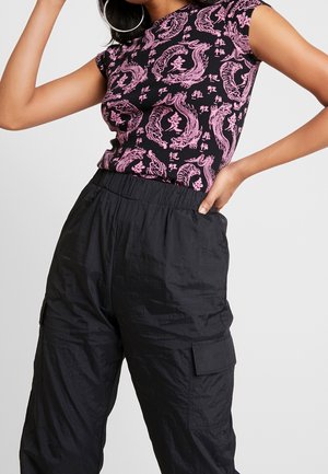 Top negro sin mangas con estampado de dragón rosa y texto, combinado con pantalones cargo negros que cuentan con bolsillos laterales, cintura elástica y tejido texturizado.