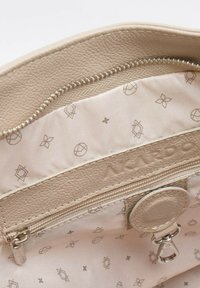 Beżowe skórzane wnętrze torby z subtelnym wzorem, zawierające kieszeń na zamek błyskawiczny i okrągłe okucia, prezentujące gładką teksturę.