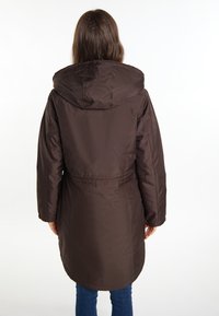 Brown, hooded long coat with a smooth texture, cinched waist, and rounded hemline. The fabric appears water-resistant.
