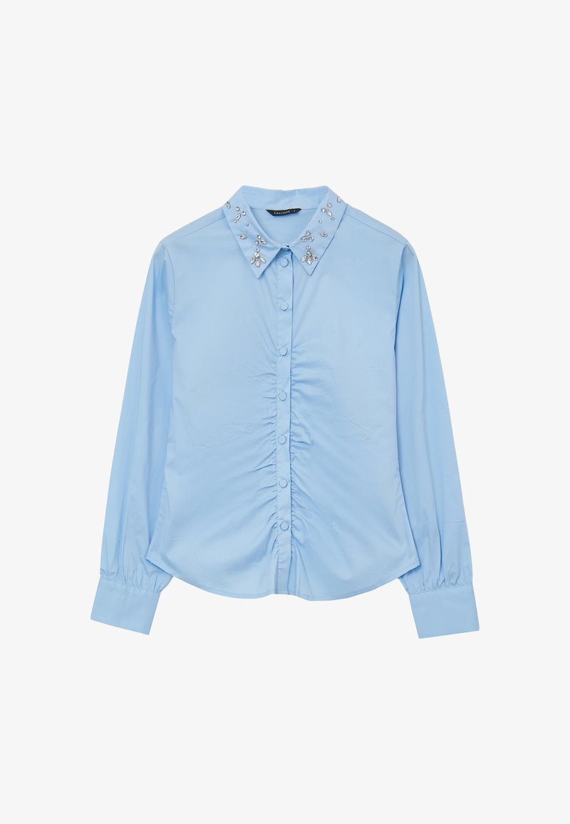 Camicia azzurro chiaro a maniche lunghe con chiusura a bottoni, dettaglio arricciato in vita e colletto decorato con gemme trasparenti.