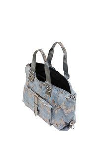 Blauwe denim tas met een zilveren pailletten-zigzagpatroon, dubbele handvatten aan de bovenkant en een voorflapzak met metalen hardware. Zwarte binnenkant.