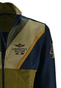 Giacca in pile con pannelli verdi, blu navy e beige. Con zip, logo "Aeronautica Militare" e un accento giallo testurizzato.