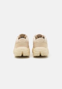 Beige sneakers med en teksturert skinnoverdel, rund form og markant gummisåle. Har preget logo på hælen og glatte detaljer.