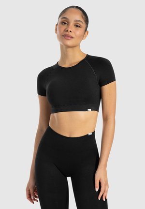 Top de sport noir court avec des manches raglan courtes et un design ajusté. Fabriqué en tissu lisse avec une large bande élastique.