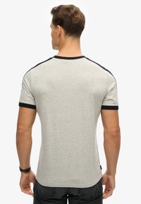 Grå T-shirt med korte ærmer og sorte detaljer på skuldre og ærmer. Fremstillet af blødt, struktureret stof; rund hals, tætsiddende design.