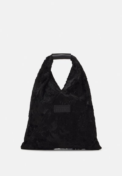 Saco tote preto com uma superfície texturizada e peluda, um topo em forma de V, e uma alça em couro liso. Apresenta um rótulo retangular na lateral.